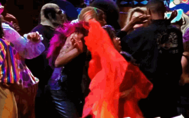 a man in a black shirt with a dragon on the back is dancing with a woman in a red dress