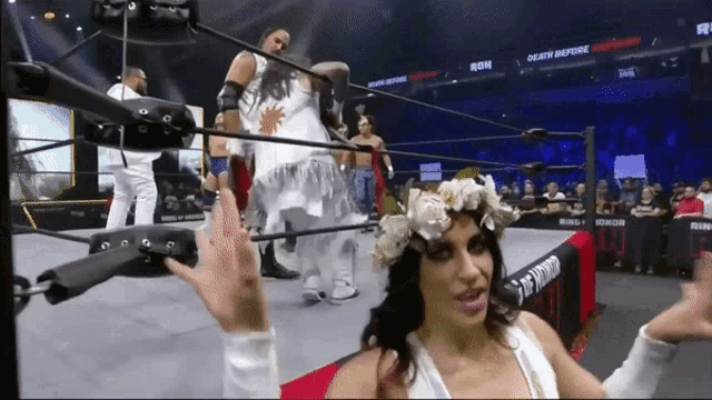 a woman wearing a flower crown stands in a wrestling ring with a sign that says death before dishonor