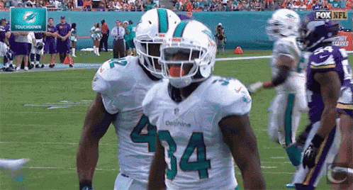 a football player with the number 434 on his jersey stands on the field .