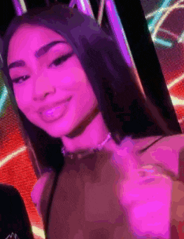 a woman is taking a picture of herself in front of a purple light .
