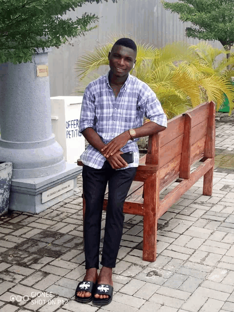 a man sitting on a bench with a sign that says offer petits
