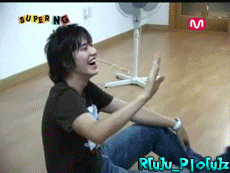 a young man is sitting on the floor in front of a fan and the words super ng are on the wall behind him
