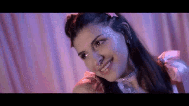 a close up of a woman wearing a pink dress and a choker smiling .