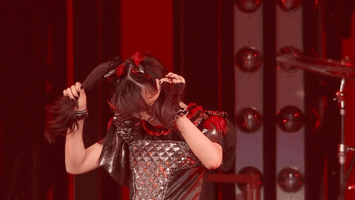 a woman is holding her hair in her hands on a stage .