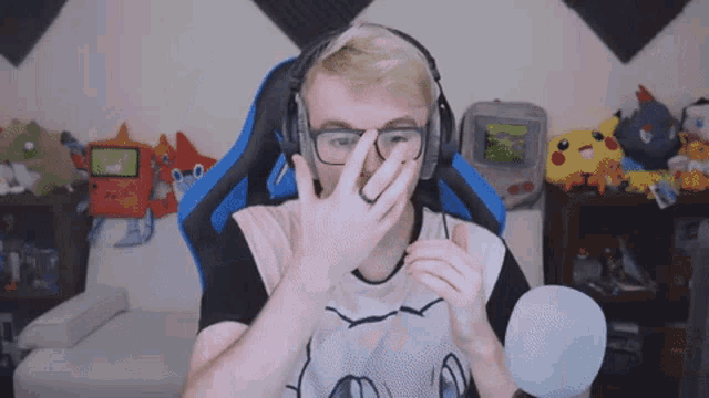 a man wearing headphones and glasses is covering his nose