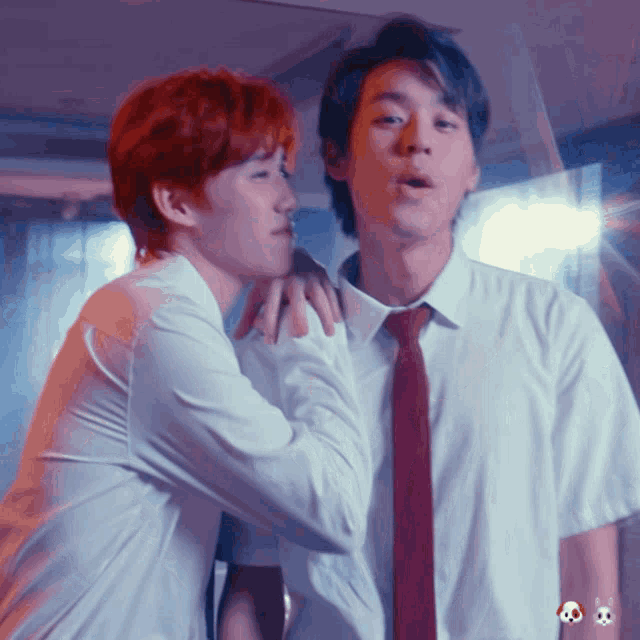 a man with red hair is whispering into the ear of another man in a white shirt and red tie