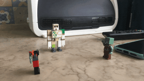 three lego figures are standing on a counter next to a phone and a remote control