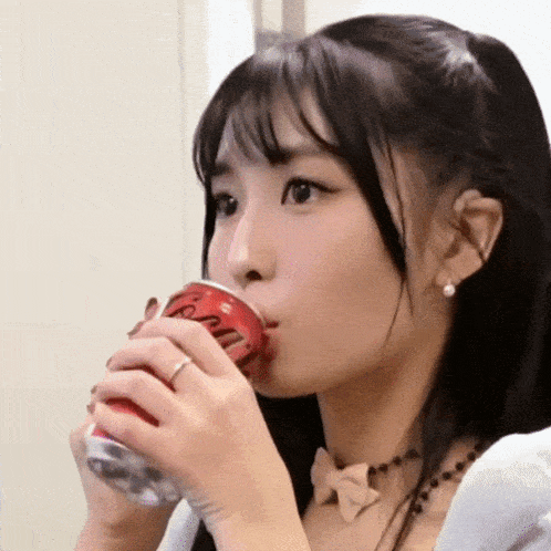 a woman is drinking a can of coca cola .