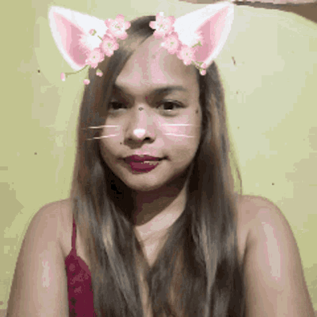 a woman with cat ears and flowers on her head looks at the camera