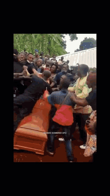 a crowd of people are gathered around a coffin with the words mundo sombrio ofc written on the bottom
