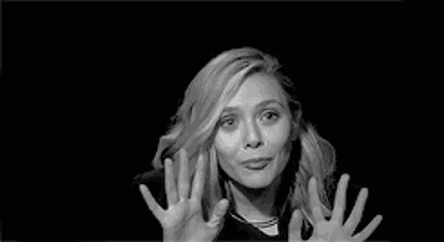 a black and white photo of a woman waving her hands in the air .