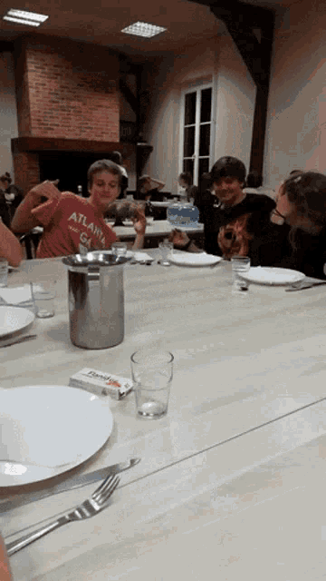 a boy in an atlanta shirt sits at a table with other people