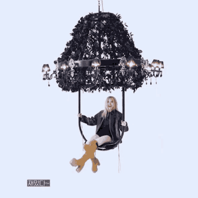 a girl is sitting on a swing under a chandelier .