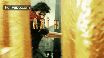 a man is standing in front of a wall holding a sword in his hand .