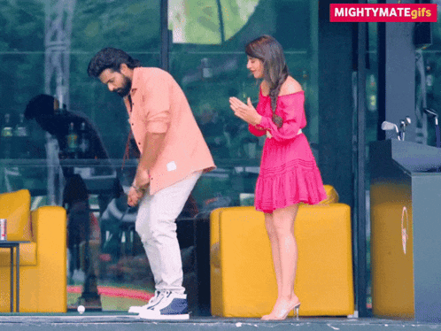 a woman in a pink dress is standing next to a man in a pink shirt who is dancing