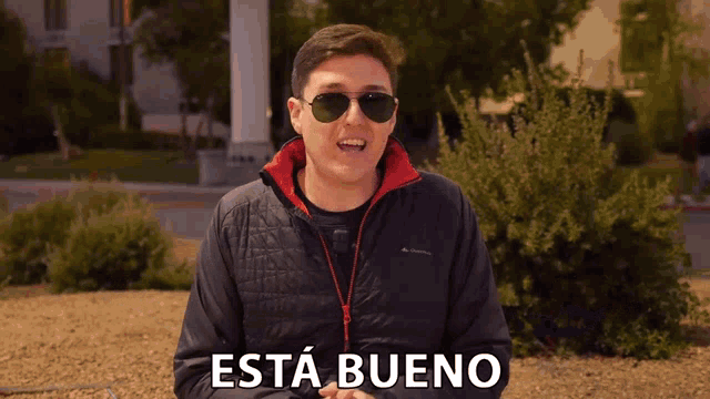 a man wearing sunglasses and a black jacket says " esta bueno "