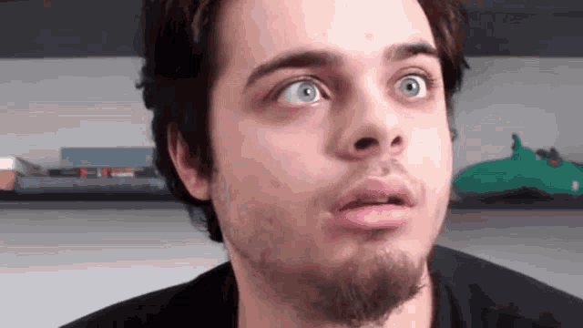 a young man with a beard is making a funny face .