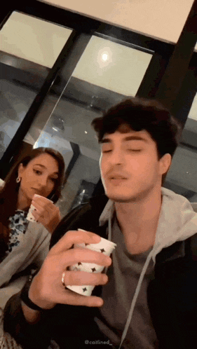 a man is holding a cup in front of a woman who is holding a cup