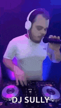 a man wearing headphones and a microphone is playing music on a turntable .