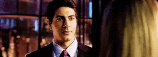a man in a suit and tie is looking at a woman in a dark room .