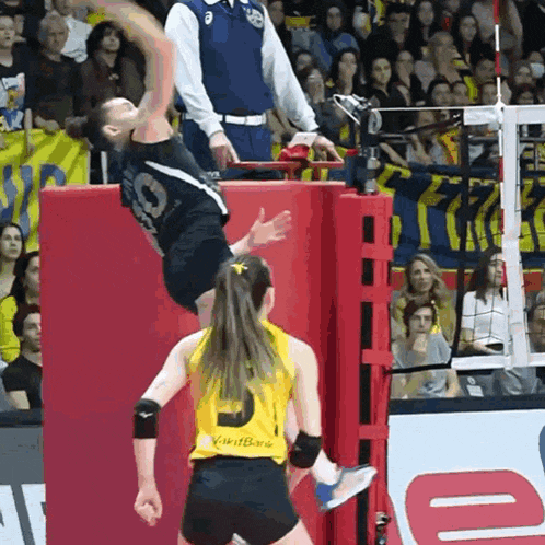 a man in a black shirt with the number 9 on it jumps over a woman in a yellow shirt with the number 9 on it