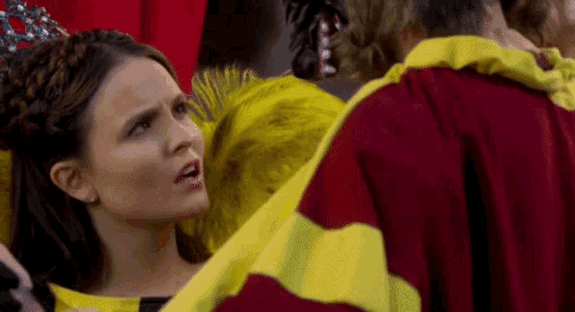 a woman in a yellow and red dress is standing next to a man in a red robe .