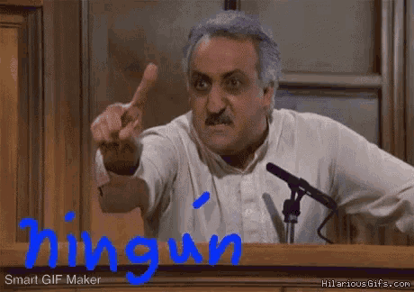 a man giving the middle finger in front of a microphone with the words " ningun " written in blue