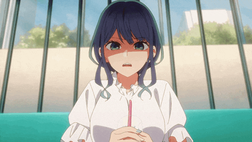 a girl with blue hair is sitting on a couch holding a drink