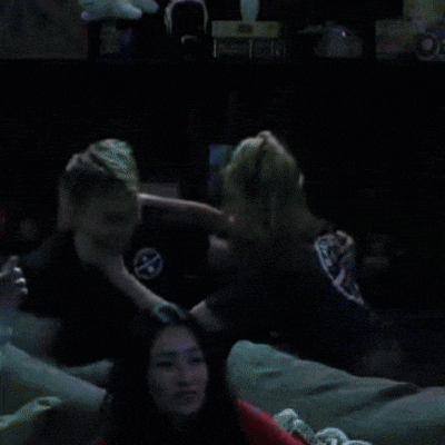 a man and a woman are fighting in a dark room and the man has a circle on his shirt