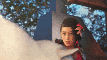 a woman with a red flower in her hair is standing next to a white cat