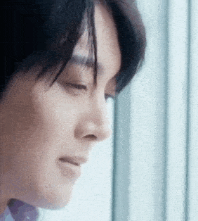 a close up of a young man 's face looking out a window .