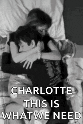 a black and white photo of a man and woman hugging each other on a bed .