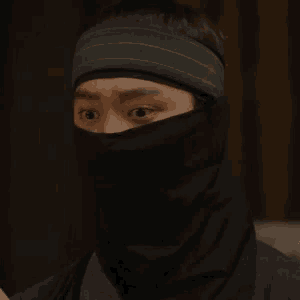 a man wearing a black headband and a black scarf covering his face