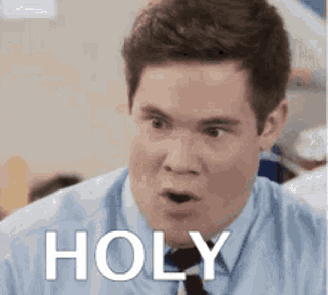 a man in a blue shirt and tie is making a surprised face with the word holy written on his face .