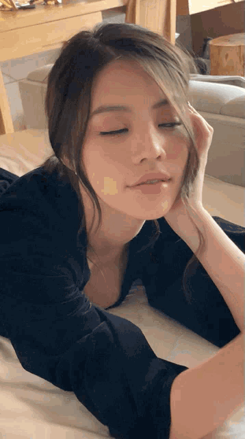 a woman with her eyes closed is laying on a bed