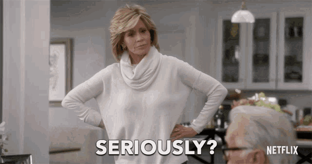 a woman in a white sweater says seriously in front of a man