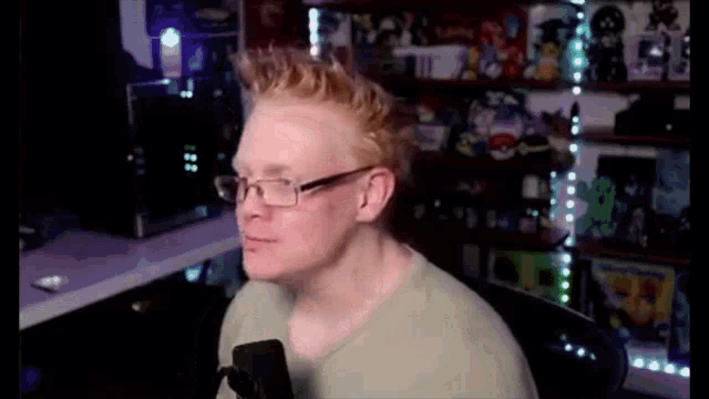 a man wearing glasses is sitting in front of a microphone in a room .