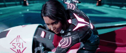 a woman in a futuristic outfit is sitting on a motorcycle with the number 121 on the side