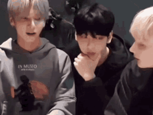 a group of young men are sitting next to each other and talking to each other .