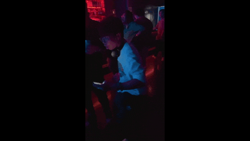 people are dancing in a dark room with red lights