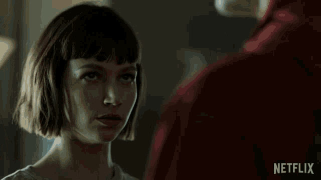 a woman is looking at a man in a red shirt with netflix written on the bottom right