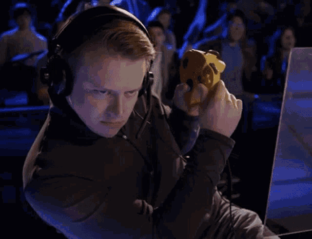 a man wearing headphones is playing a video game with a yellow controller