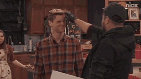 a man in a plaid shirt is being slapped in the face by a man in a green hoodie