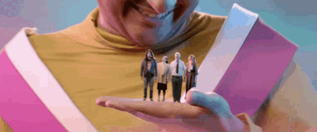 a man in a yellow shirt is holding a small group of people in his hand