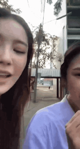 a couple of women are standing next to each other on a street .