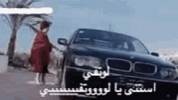 a woman in a red dress is standing next to a bmw car .