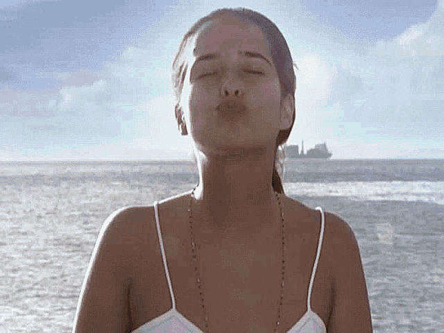a woman is blowing a kiss while standing on a beach .
