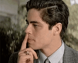 a man in a suit and tie is holding his finger to his mouth .