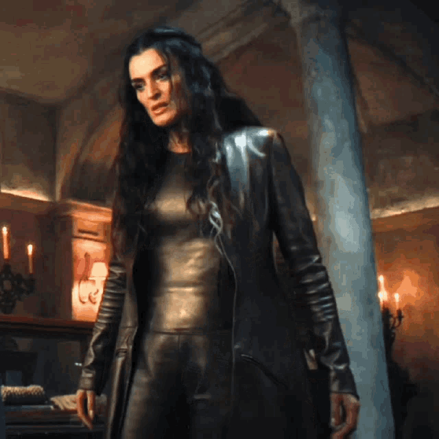 a woman in a black leather outfit stands in a room