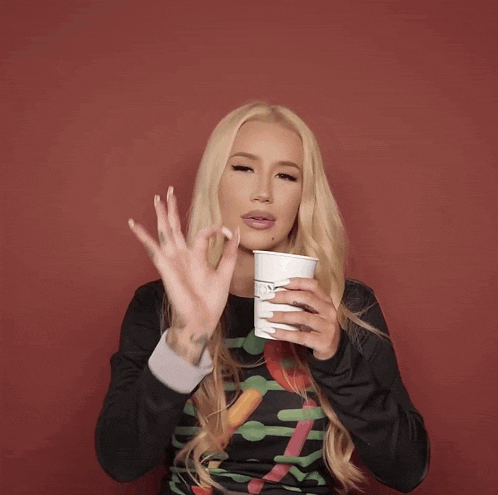 a woman with long blonde hair is drinking from a cup with the letter n on it